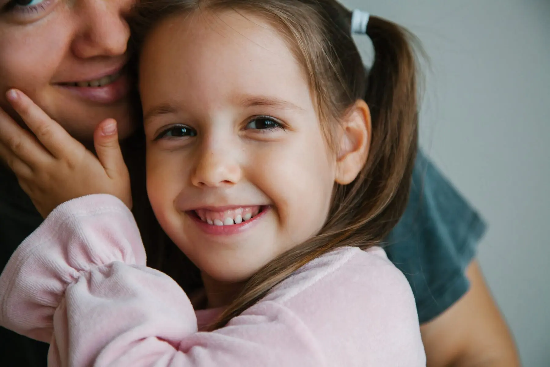 A Smiling Mother and Daughter looking into camera.