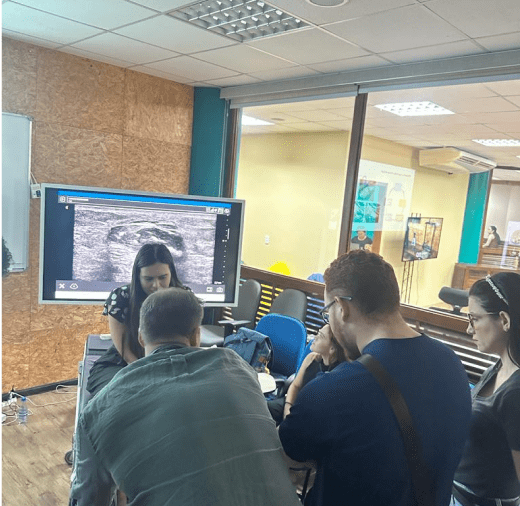 Instructor demonstrating ultrasound techniques to a group of students in a specialized training room.