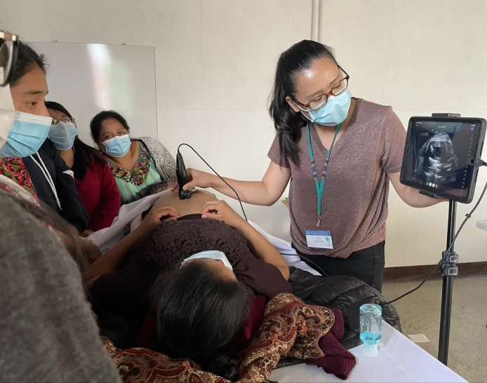 Demonstrating Ultrasound Usage, multiple women looking at monitor being presented by female clinician