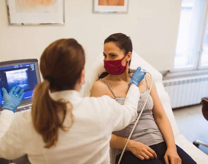 Female clinician using ultrasound technology to scan another womans neck