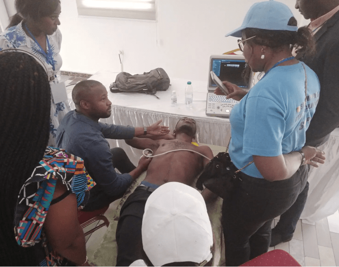 Clinician demonstrating ultrasound technology on participant while several other clinicians observe and record