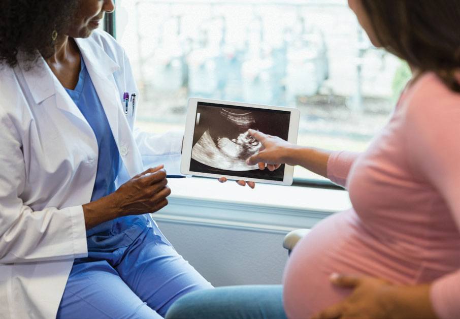 Woman pointing at sonogram picture in clinicians hand